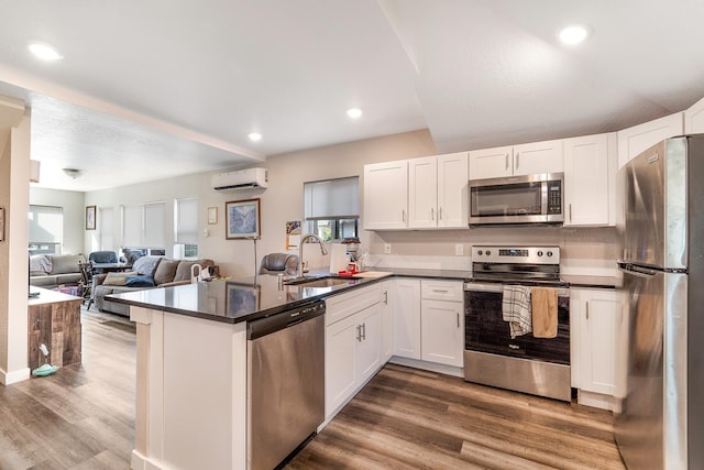2213 E E Gordon Ave, Spokane, WA 99207 - kitchen featuring stainless steel appliances, a sink, a wall unit AC, dark countertops, and wood finished floors