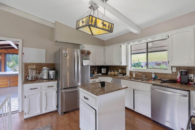 kitchen featuring white cabinets, sink, a kitchen island, stainless steel appliances, and decorative backsplash