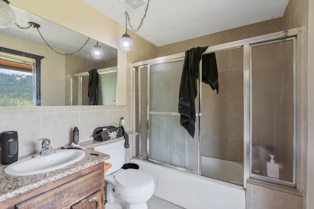 full bathroom featuring tile walls, decorative backsplash, vanity, enclosed tub / shower combo, and toilet