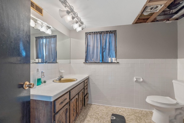 bathroom with tile walls, tile patterned flooring, vanity, and toilet