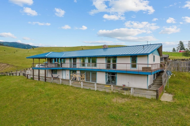 rear view of property with a mountain view and a lawn