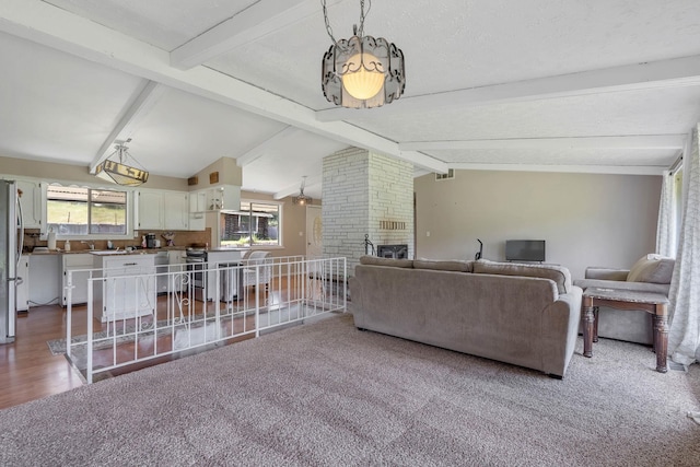 living room featuring carpet, vaulted ceiling with beams, and a fireplace