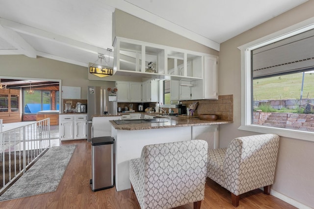 kitchen with lofted ceiling with beams, light wood-type flooring, white cabinets, kitchen peninsula, and decorative backsplash