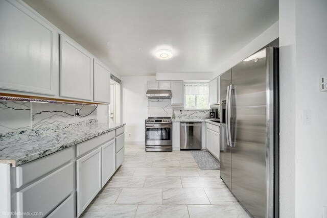 kitchen with light stone countertops, backsplash, and appliances with stainless steel finishes