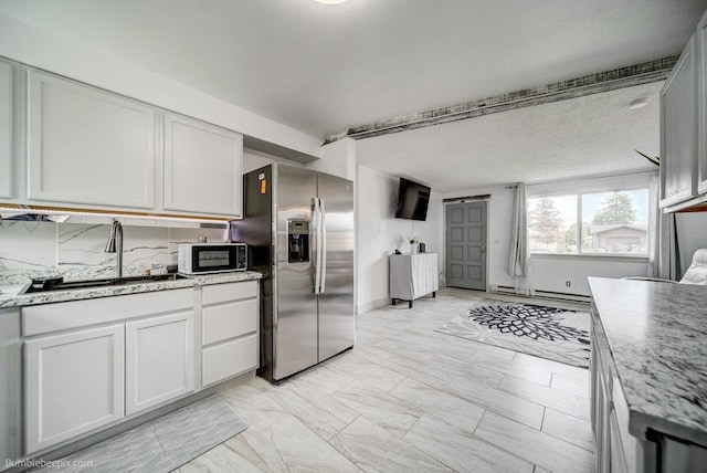 kitchen featuring light stone counters, a textured ceiling, sink, white cabinetry, and stainless steel fridge