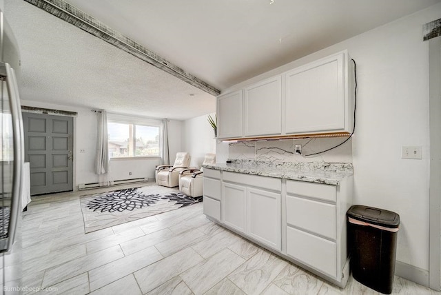 kitchen with a baseboard heating unit, white cabinets, a textured ceiling, and light stone countertops