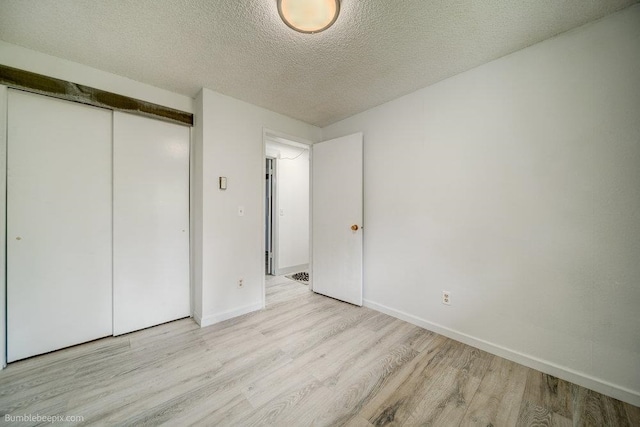 unfurnished bedroom featuring a textured ceiling, a closet, and light hardwood / wood-style floors