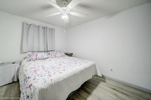 bedroom featuring a textured ceiling, wood-type flooring, and ceiling fan