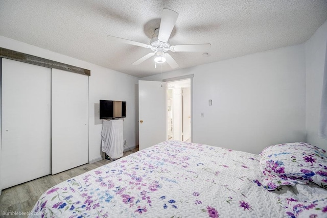 bedroom featuring ceiling fan, a textured ceiling, light hardwood / wood-style flooring, and a closet