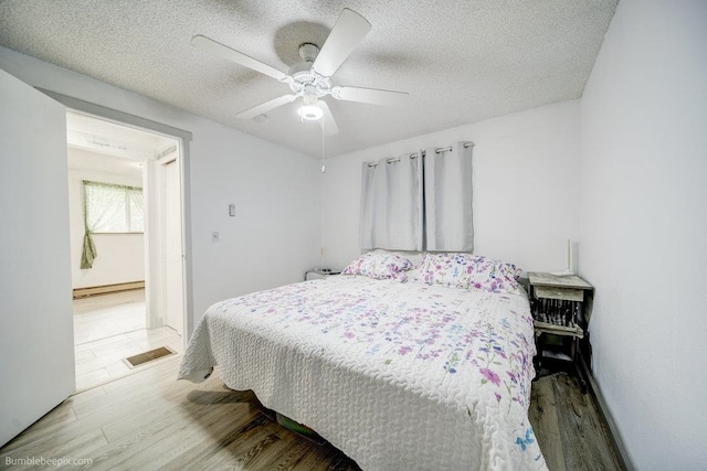 bedroom featuring ceiling fan, a textured ceiling, and light hardwood / wood-style floors