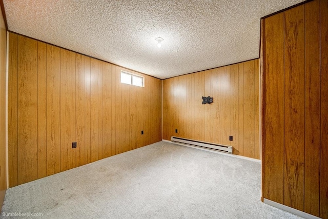 basement featuring carpet floors, wooden walls, baseboard heating, and a textured ceiling