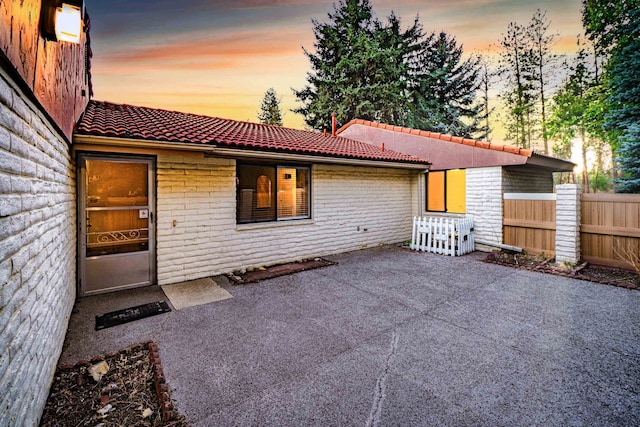 back house at dusk with a patio area