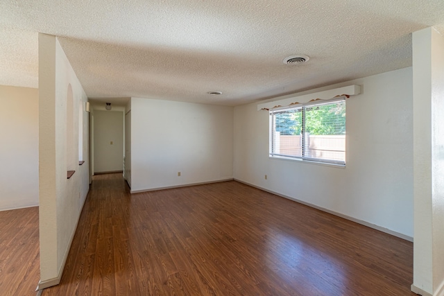 spare room featuring a textured ceiling and dark hardwood / wood-style floors