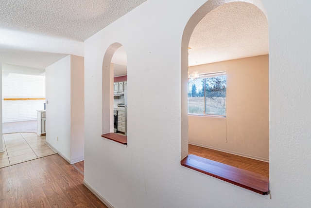 corridor featuring an inviting chandelier, wood-type flooring, and a textured ceiling