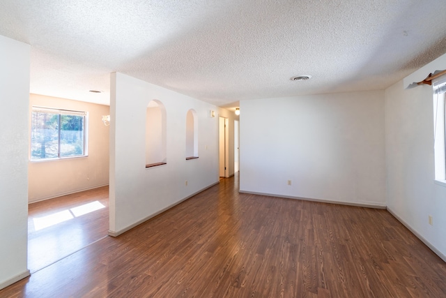 spare room with a textured ceiling and dark wood-type flooring