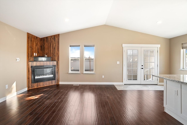 unfurnished living room with french doors, vaulted ceiling, dark hardwood / wood-style floors, and a fireplace