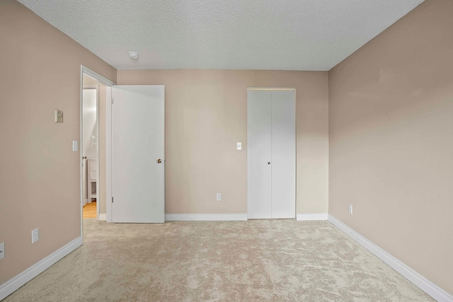 unfurnished bedroom featuring a textured ceiling and light carpet