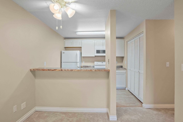 kitchen featuring ceiling fan, kitchen peninsula, white appliances, light hardwood / wood-style flooring, and white cabinetry