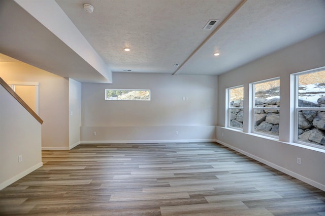 spare room with a textured ceiling and light hardwood / wood-style flooring