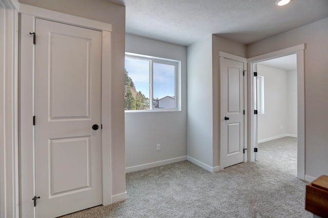 corridor featuring light colored carpet and a textured ceiling