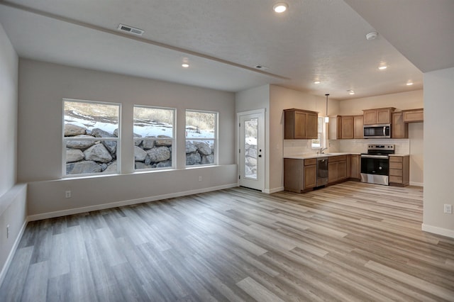 18513 E Michielli Ln, Spokane Valley, WA 99016 - kitchen featuring appliances with stainless steel finishes, light countertops, light wood-style floors, recessed lighting, and brown cabinets