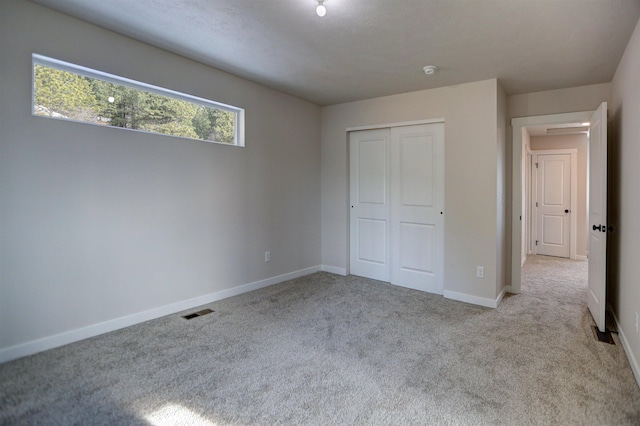 unfurnished bedroom with light carpet and a closet