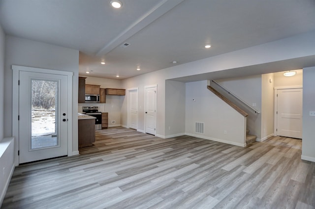 unfurnished living room featuring beam ceiling and light wood-type flooring