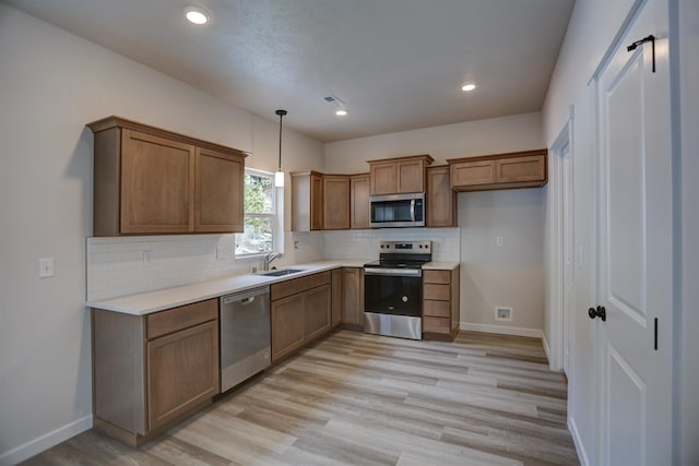 18513 E Michielli Ln, Spokane Valley, WA 99016 - kitchen featuring appliances with stainless steel finishes, brown cabinetry, light wood finished floors, decorative backsplash, and pendant lighting