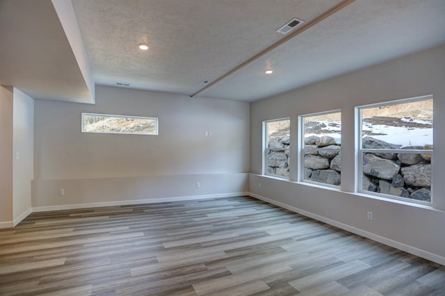 spare room with light hardwood / wood-style flooring and a textured ceiling