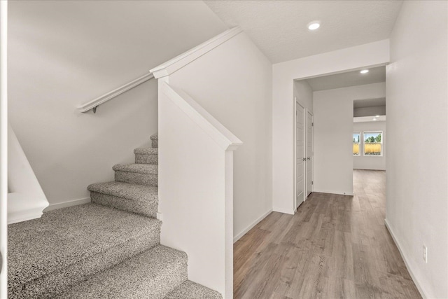 stairs featuring a textured ceiling and hardwood / wood-style floors