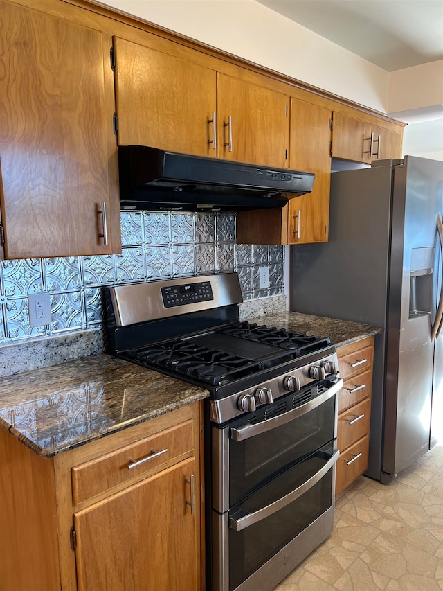 kitchen featuring dark stone countertops, stainless steel gas range oven, and backsplash