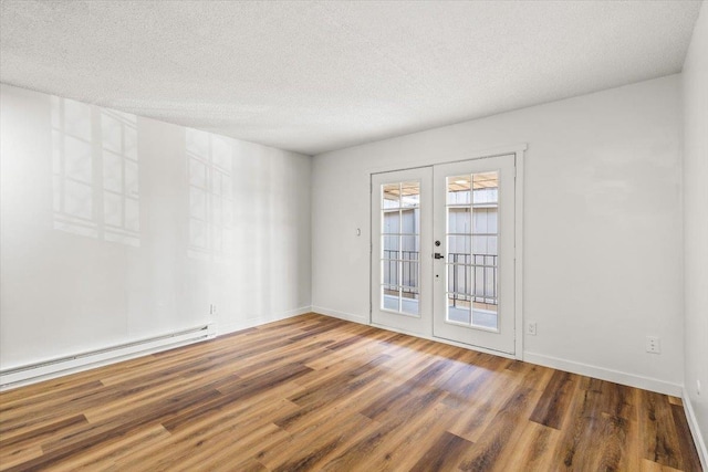 spare room featuring a textured ceiling, baseboard heating, french doors, and dark hardwood / wood-style flooring