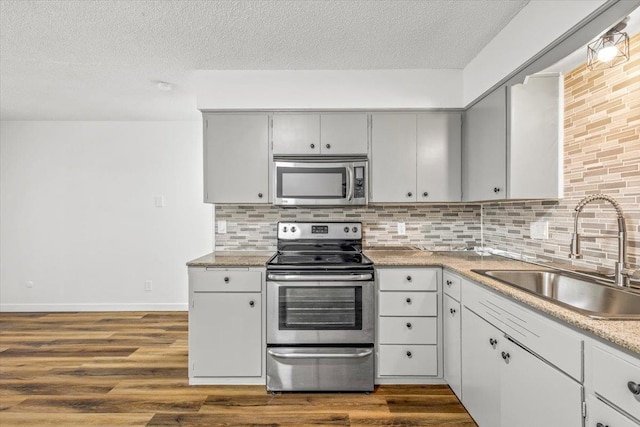 kitchen with a textured ceiling, appliances with stainless steel finishes, dark hardwood / wood-style floors, and sink