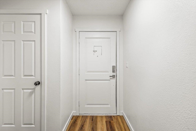 doorway with a textured ceiling and dark hardwood / wood-style floors