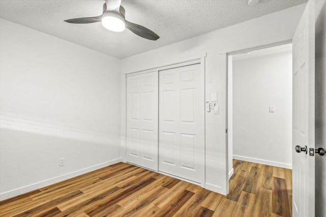 unfurnished bedroom featuring a textured ceiling, wood-type flooring, ceiling fan, and a closet