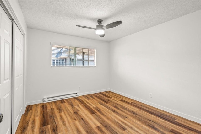 empty room featuring a baseboard heating unit, wood-type flooring, ceiling fan, and a textured ceiling