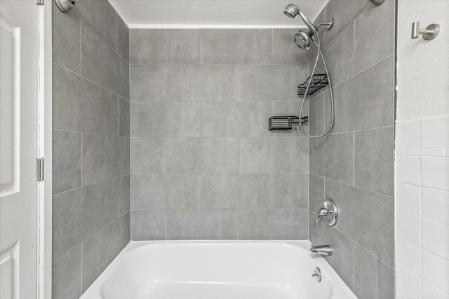 bathroom featuring a textured ceiling and tiled shower / bath combo