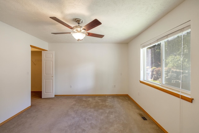 carpeted spare room with a textured ceiling and ceiling fan