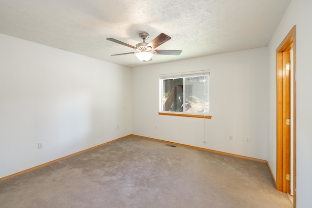 carpeted spare room featuring ceiling fan and a textured ceiling