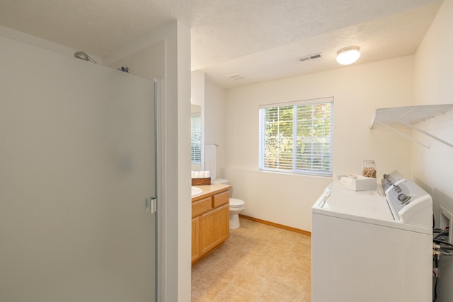 washroom with a textured ceiling and washing machine and dryer