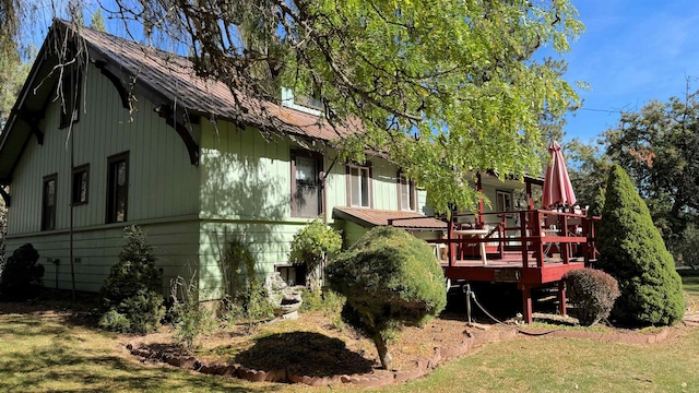 rear view of house featuring a lawn and a deck