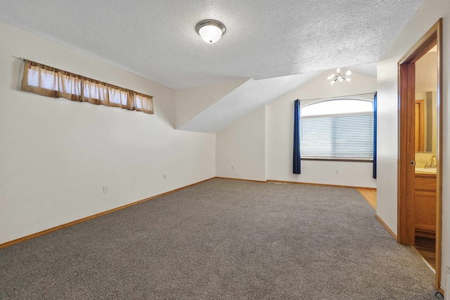 bonus room featuring carpet flooring, sink, a textured ceiling, a notable chandelier, and vaulted ceiling