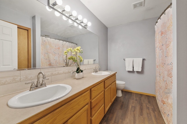 bathroom with vanity, hardwood / wood-style flooring, toilet, and tasteful backsplash