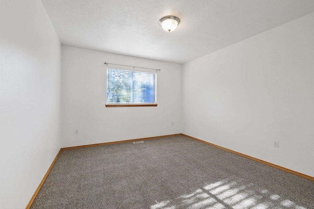 empty room with a textured ceiling and carpet flooring