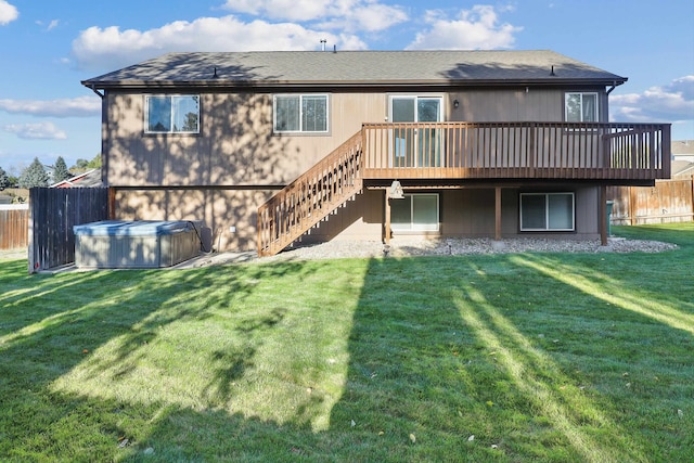 rear view of property with a wooden deck, a hot tub, and a yard