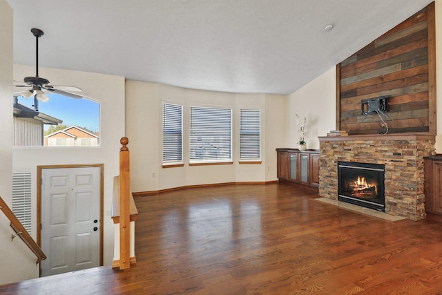 living room with lofted ceiling, ceiling fan, dark hardwood / wood-style floors, and a stone fireplace