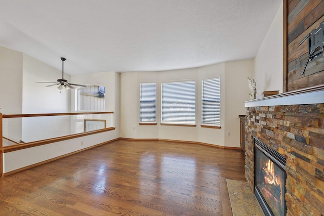 unfurnished living room with ceiling fan, vaulted ceiling, a fireplace, and dark hardwood / wood-style flooring