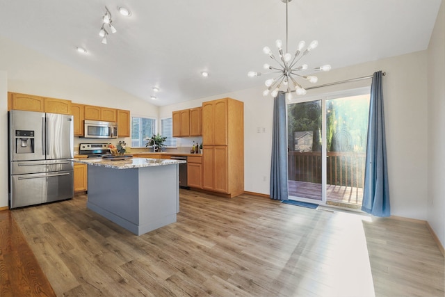 kitchen featuring light stone counters, lofted ceiling, a kitchen island, light hardwood / wood-style flooring, and stainless steel appliances