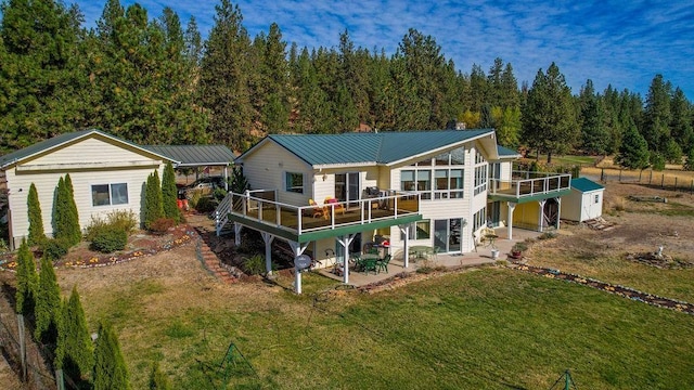 back of house with a patio area, a deck, a yard, and a storage shed