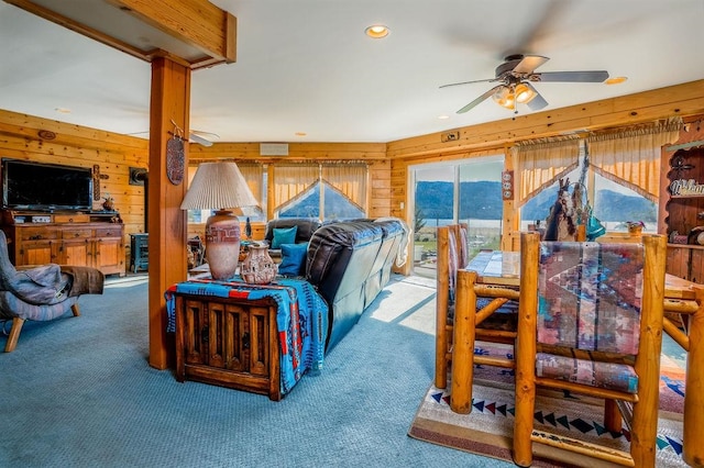 living room with ceiling fan, wooden walls, and carpet flooring